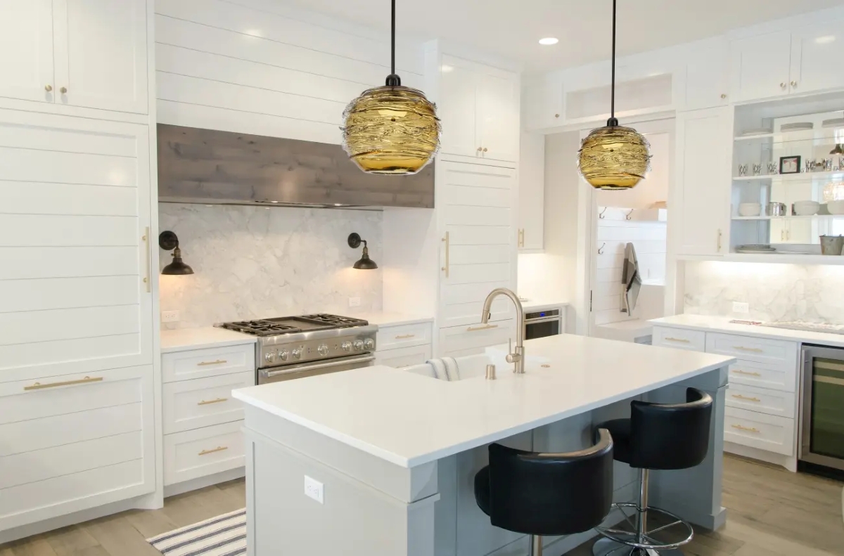 Nowoczesna kuchnia w jasnych barwach z wyspą kuchenną, czarnymi hokerami i inteligentnym oświetleniem nad blatem oraz szafkami.